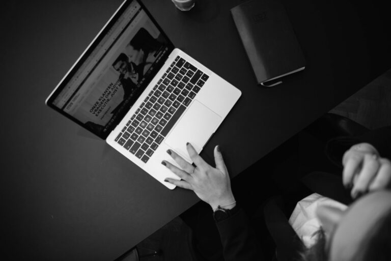 Een laptop op een bureau van bovenaf gefotografeerd met een hand die rust op de laptop, ter ondersteuning van de use case afbouwen effectenkrediten